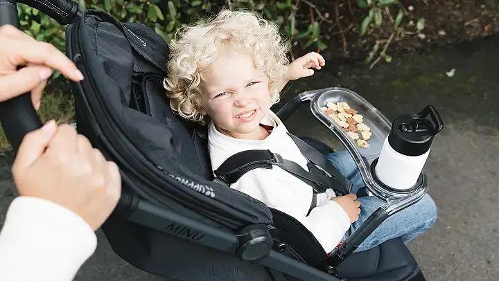 child using snack tray on stroller