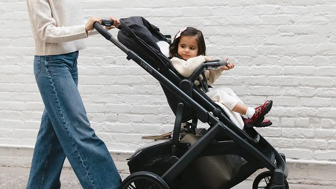 Mother pushing stroller, snack tray attached to stroller